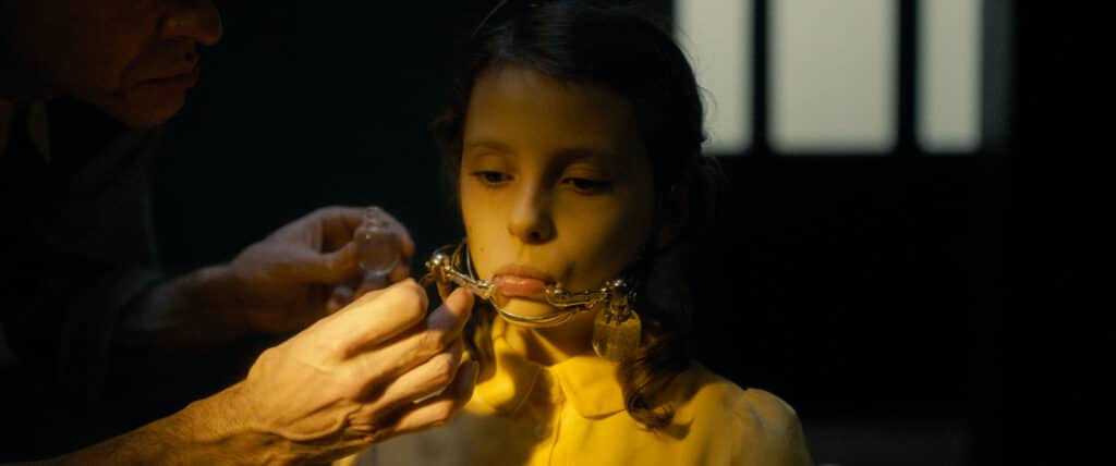 petite fille qui porte un appareil autour de la mâchoire visant à lui reconstituer sa dentition de glace